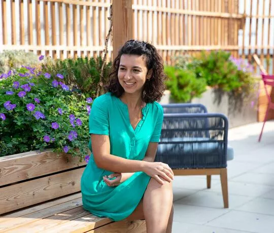 Jeune femme avec une robe verte assise sur un banc
